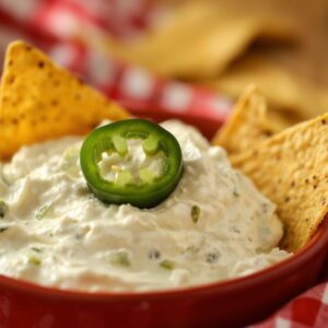 jalapeno popper dip in a red bowl served with tortilla chips