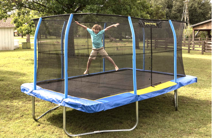 Boy in green shirt jumping on a rectangle trampoline