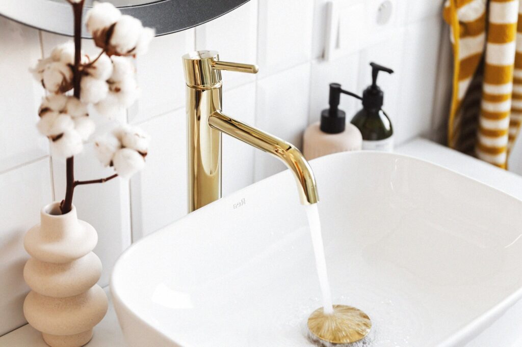 Gold faucet running water into a clean white sink — shining the sink with lemon