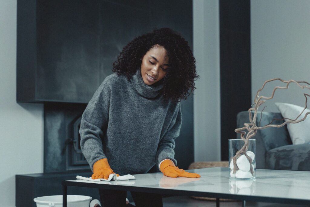 Person in rubber gloves wiping down a table — disinfecting surfaces with rubbing alcohol