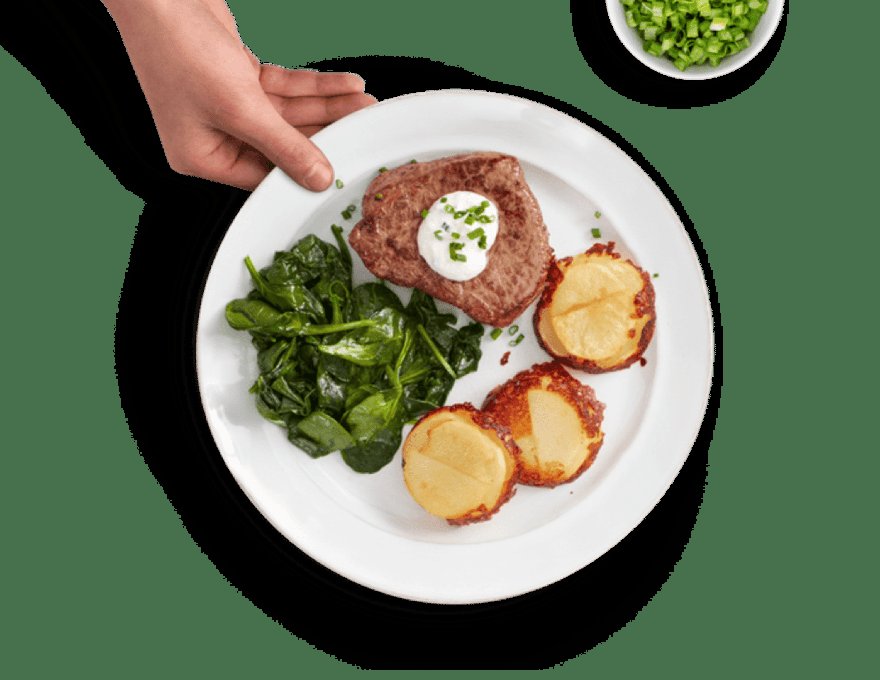 Home Chef steak dinner with crispy potatoes and sauteed spinach on a white plate